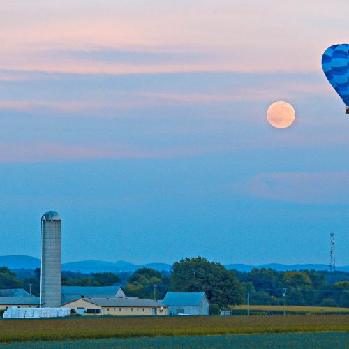 une montgolfière, le soleil et une ferme
