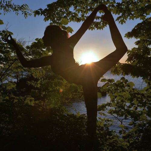 Yoga dans les bois, sur le bord de l'eau au couché du soleil