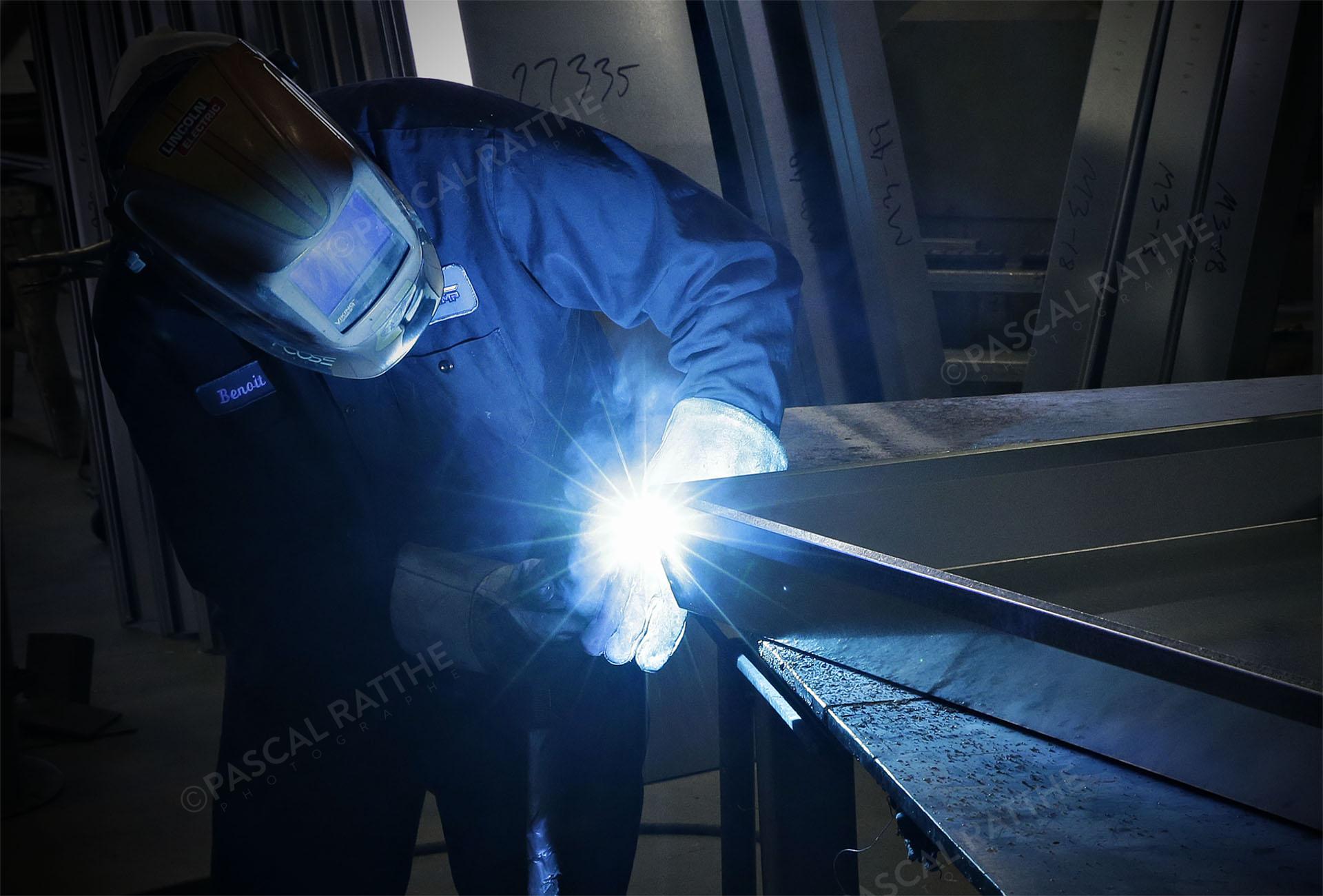 photo d'un soudeur qui soude des plaques d'aluminium ce qui produit une belle lumière bleu