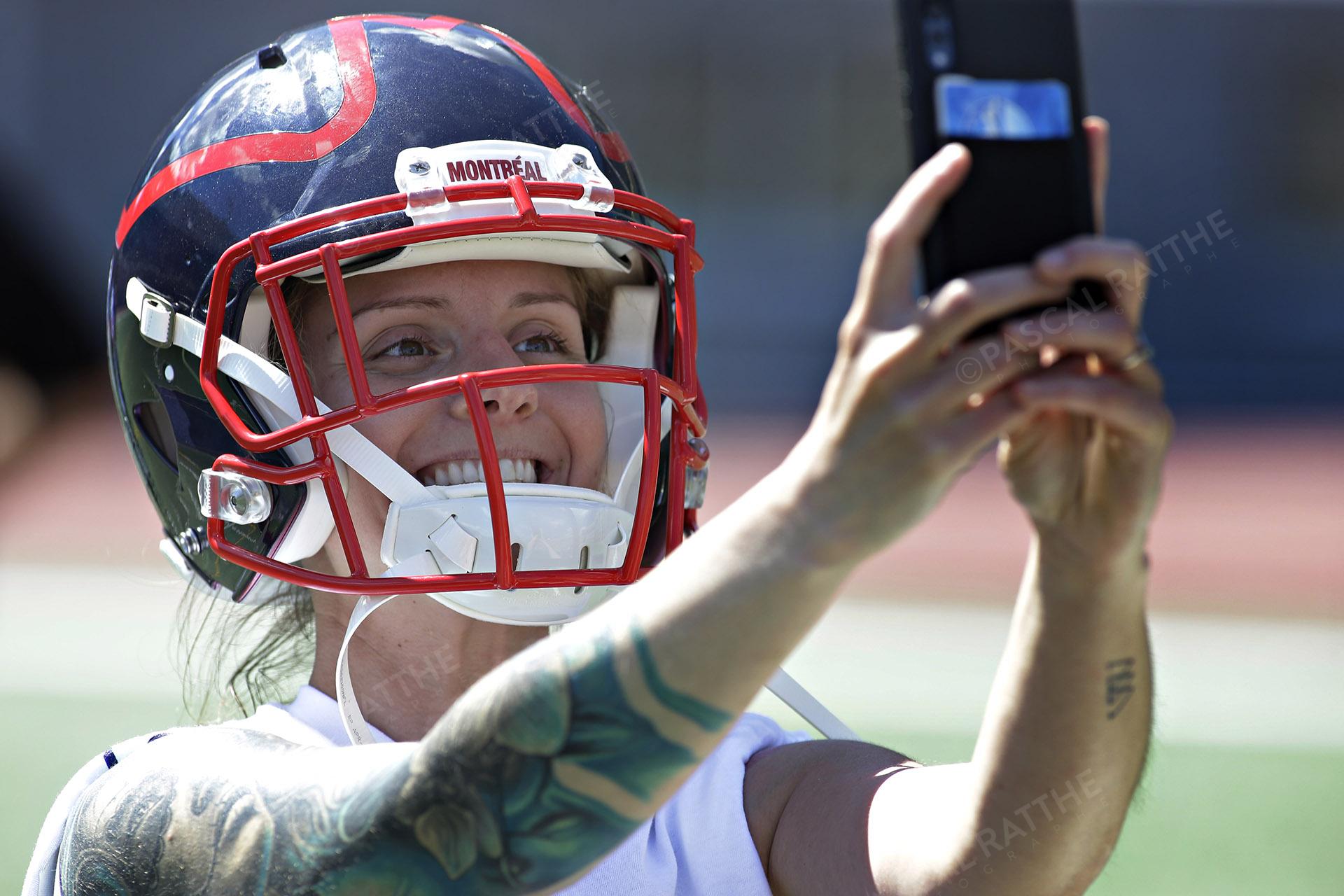 une fan des Alouettes de Montréal se prend en Selfie avec un Casque de Football à la clinique de football
