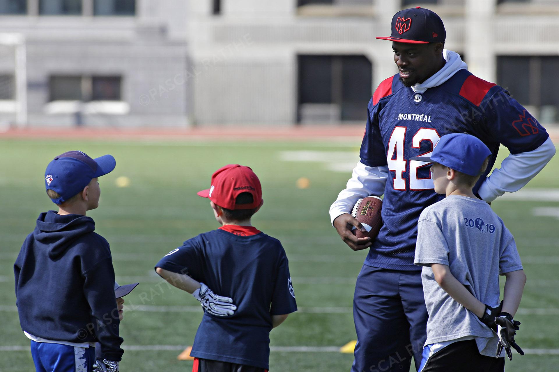 Cliniques Football des Alouettes de Montréal plusieurs enfants avec un joueur des Alouettes Blanc, Jean-Samuel