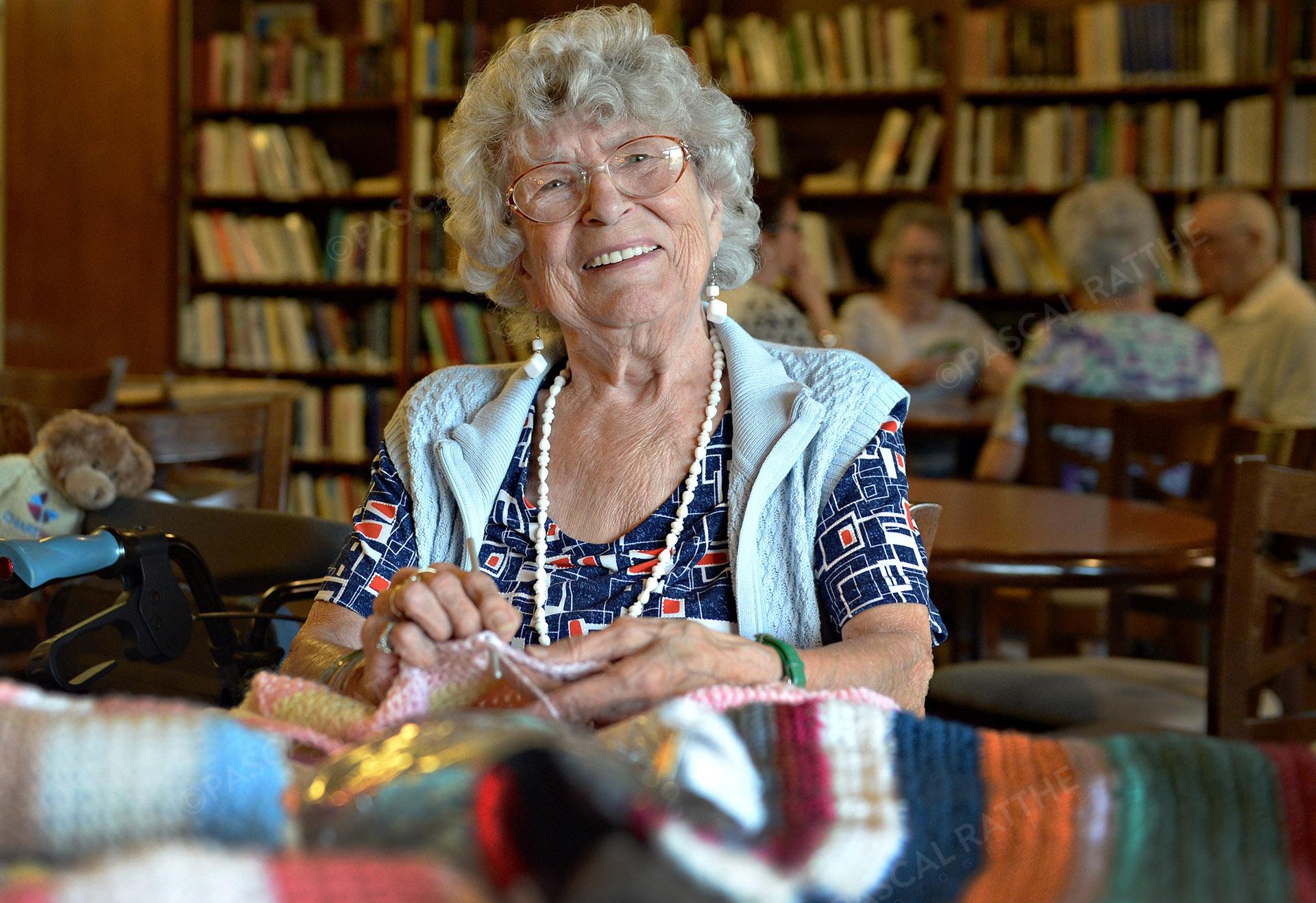 les mainpersonne âgé avec un grand sourirefaisant du tricot