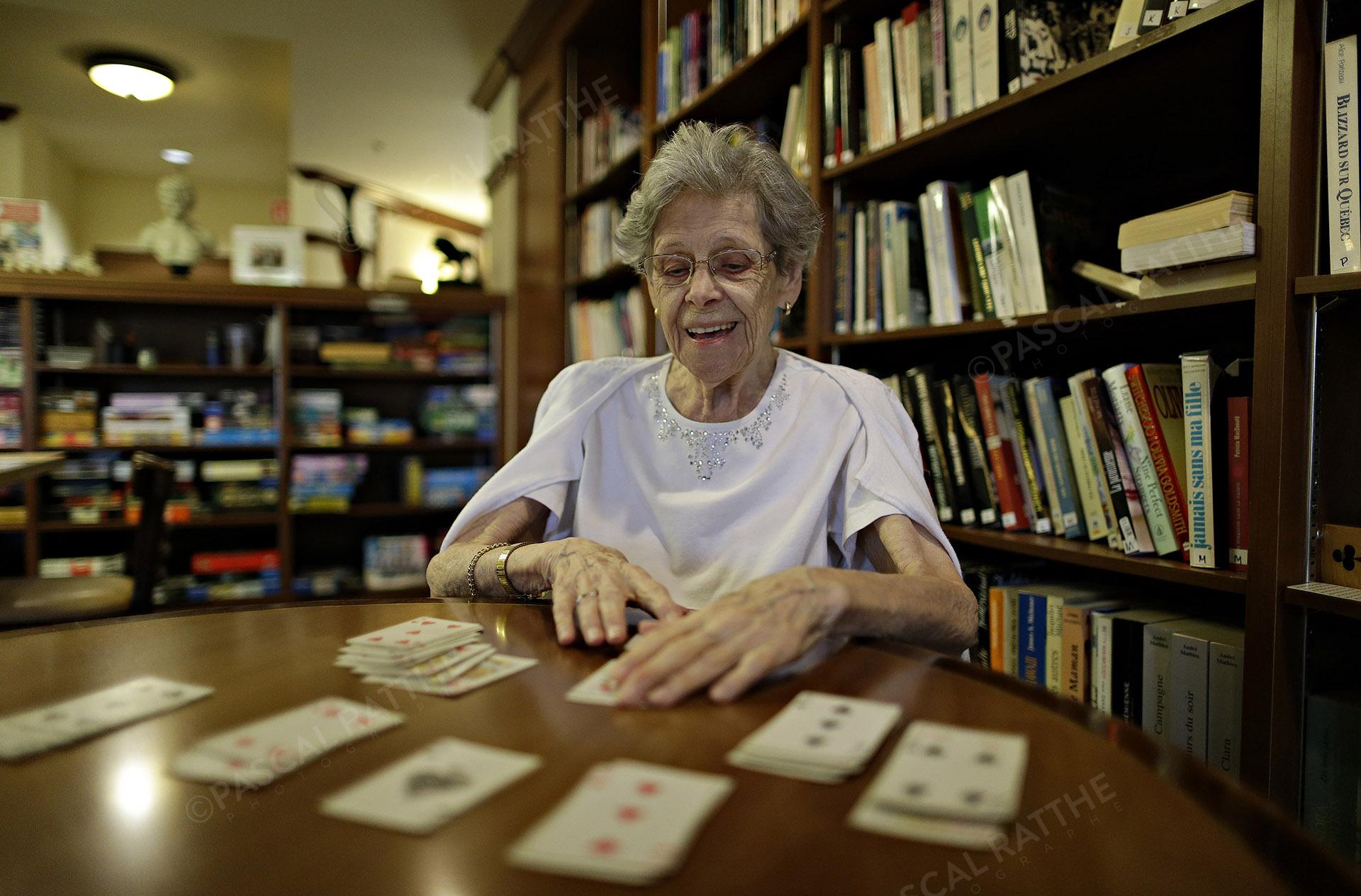 une dame du 3e âge avec un sourire éclantant jouant aux cartes